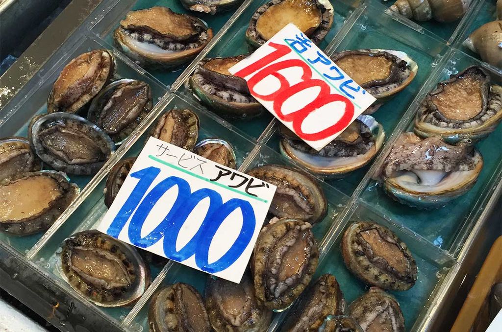 Assorted sizes of awabi abalone at a Japanese market with price tags in yen.