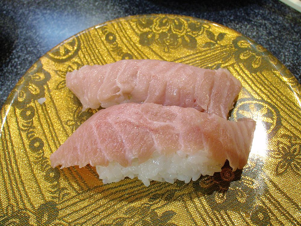 Zwei Stücke Bincho Toro Nigiri Sushi, serviert auf einem goldverzierten Teller, der die edle Einfachheit der japanischen Sushi-Kunst betont.