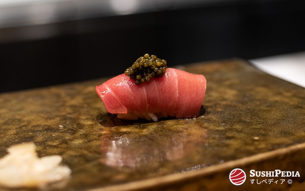 Chutoro Bluefin tuna sushi nigiri topped with glistening beads of sturgeon caviar on a rustic stone plate