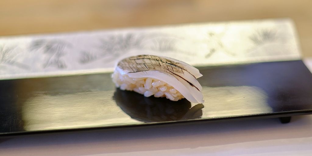 Sepia nigiri sushi, meticulously presented on a black rectangular plate, reflecting the elegance of traditional sushi craft.