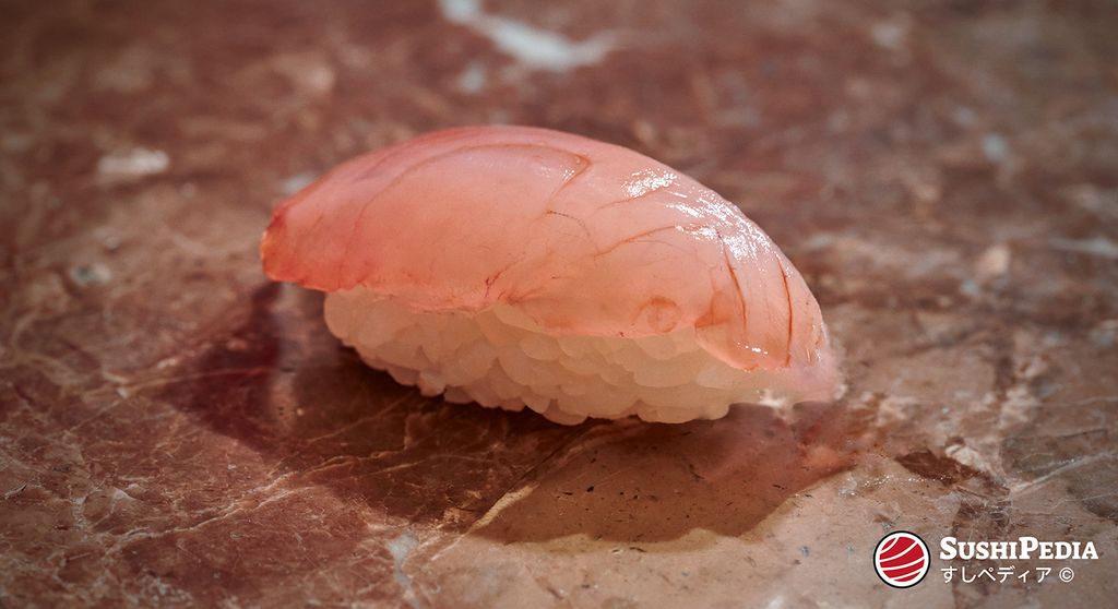 A piece of Kanpachi nigiri sushi on a marble surface.