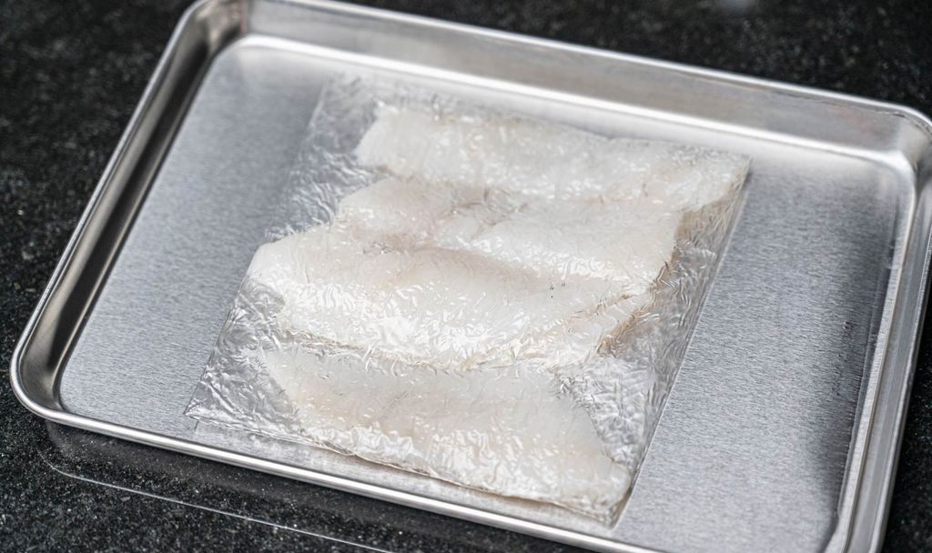 Pieces of sashimi on a tray, wrapped in Pichitto film for dehydration. The film helps remove excess moisture and preserve the freshness of the fish.