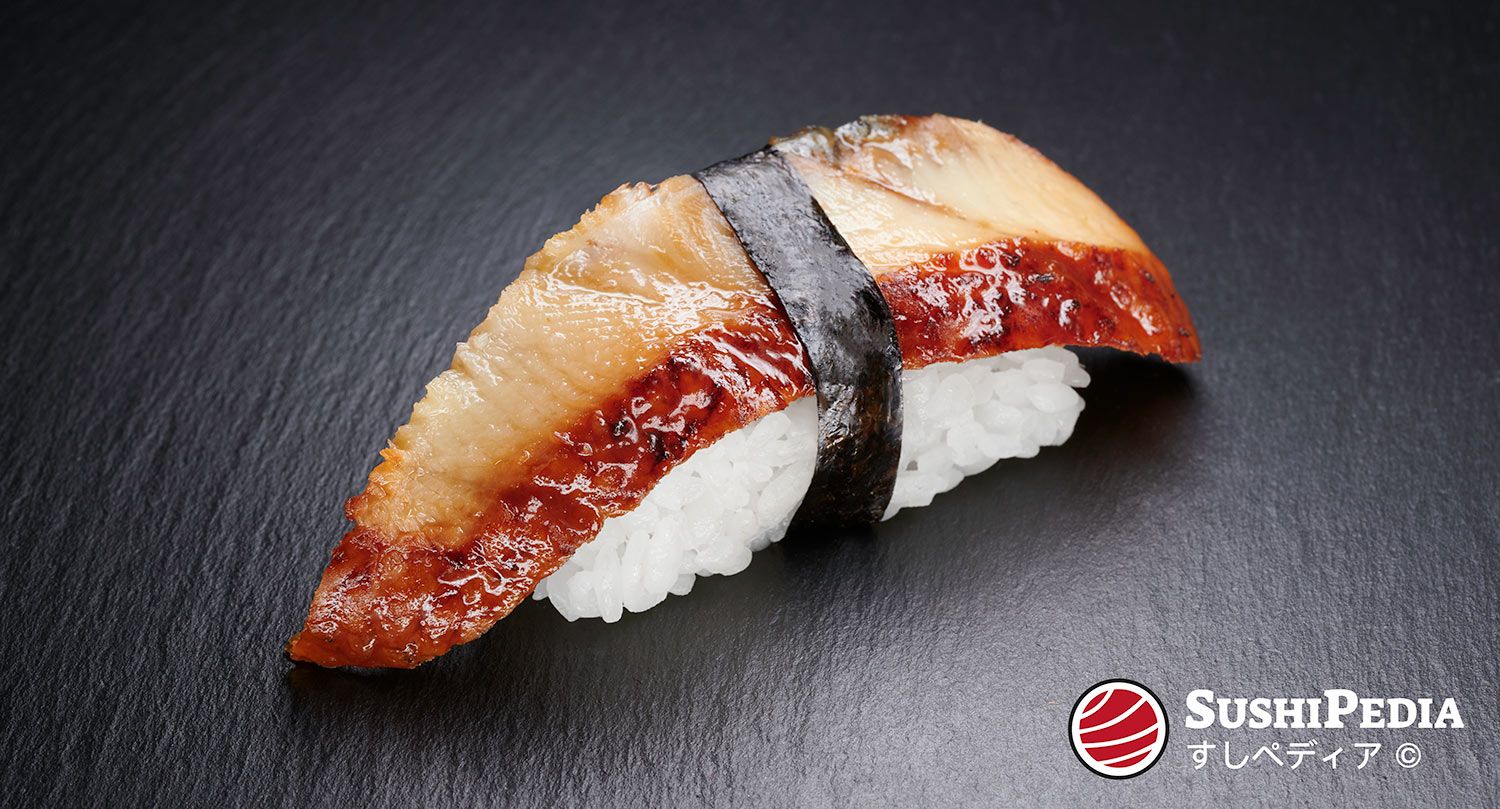 A piece of Unagi Nigiri sushi, featuring a glossy, grilled eel slice atop a bed of fluffy white sushi rice, wrapped with a thin strip of Nori seaweed. The sushi is presented on a dark, slate-colored surface, with the SushiPedia logo in the bottom right corner.