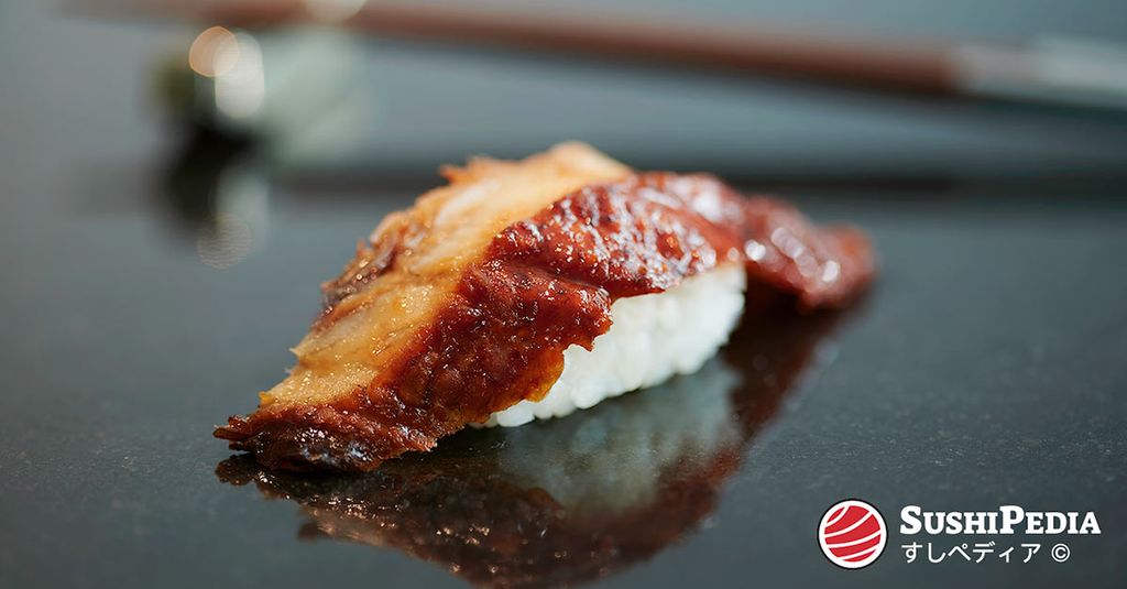 Ein frisch zubereitetes Stück Aal Sushi liegt auf einer Servierplatte.