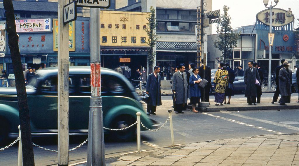 Tokyo 1952, bustling Ginza district with pedestrians and vintage cars, illustrating the post-war economic recovery and culinary expansion.