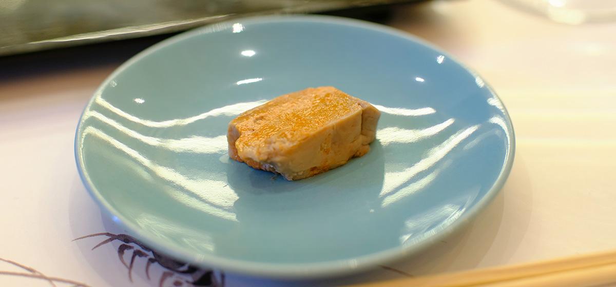 A piece of sliced ankimo lies on a plate.